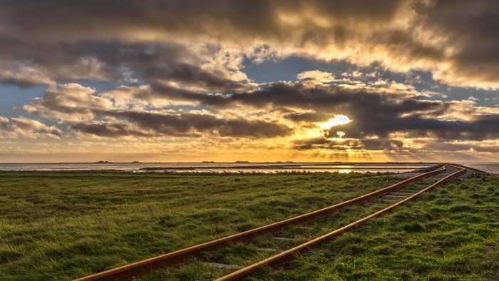 Railroad tracks leading to the sea at sunrise