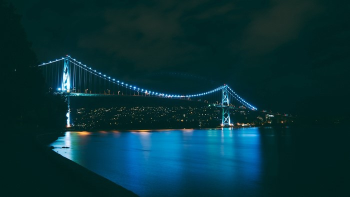 Night view of Lions Gate Bridge illuminated with blue lights