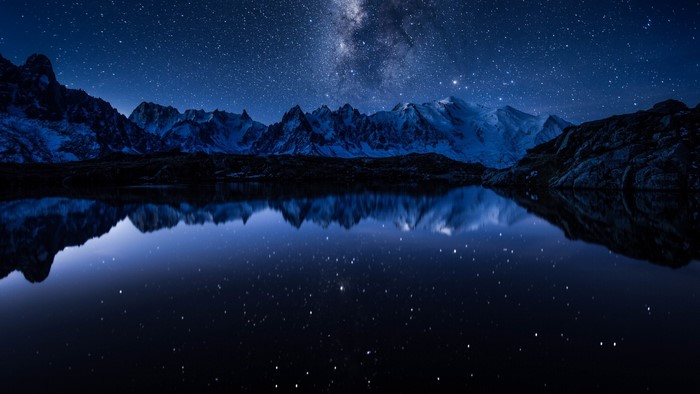 Starry night sky reflected in a mountain lake