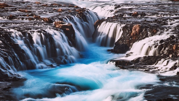 Blue cracked stream waterfall over dark rocks