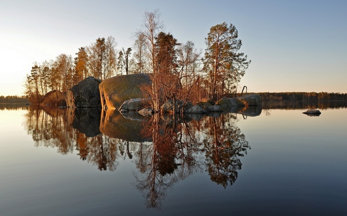 Island with trees and rocks reflected in water