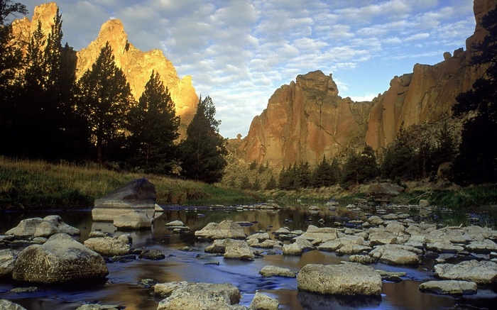 River flowing past rocky cliffs and trees at sunset