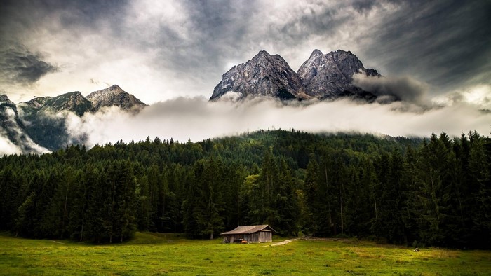 Mountains with clouds and a cabin