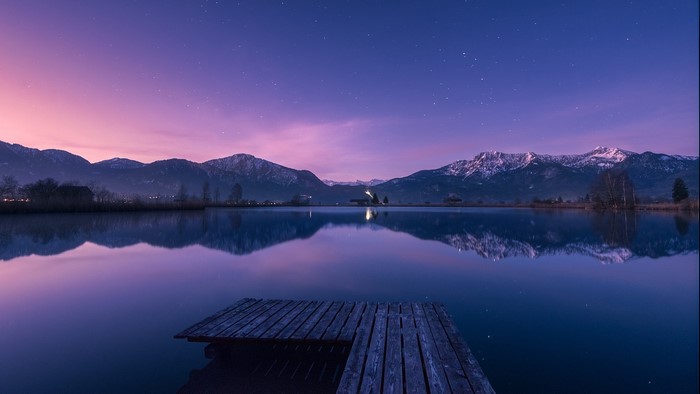 Wooden dock on a calm lake with Bavarian Alps at twilight