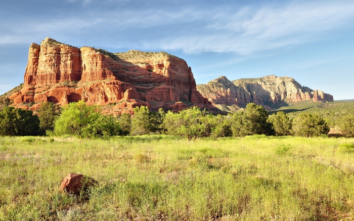 Red rock formations and green meadow under a blue sky