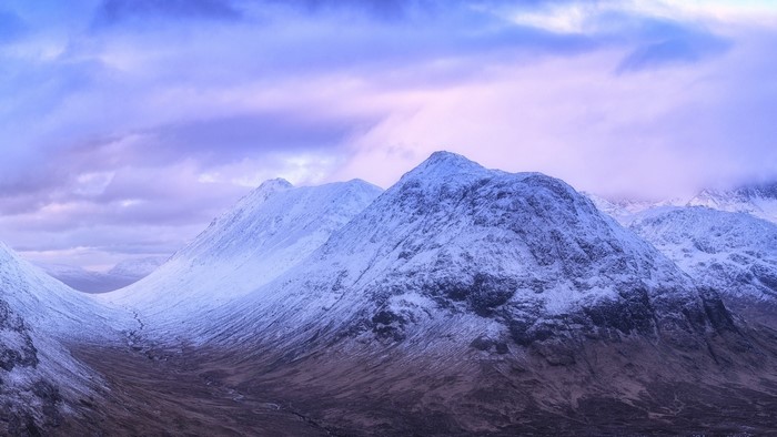 Snow-covered mountains under a purple sky