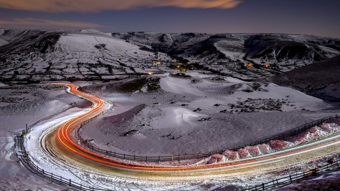 Winding road through snowy mountains at night