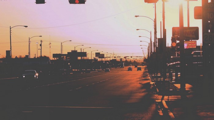 Sunset over a highway with cars and traffic lights