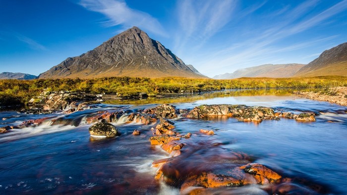 Mountain river with rocky foreground and golden hills