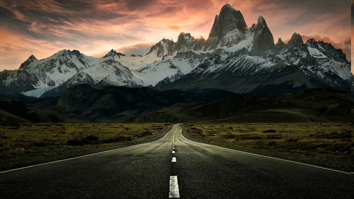 Road leading to snow-capped mountains at sunset
