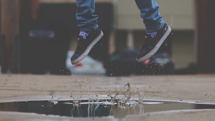Person jumping over a puddle