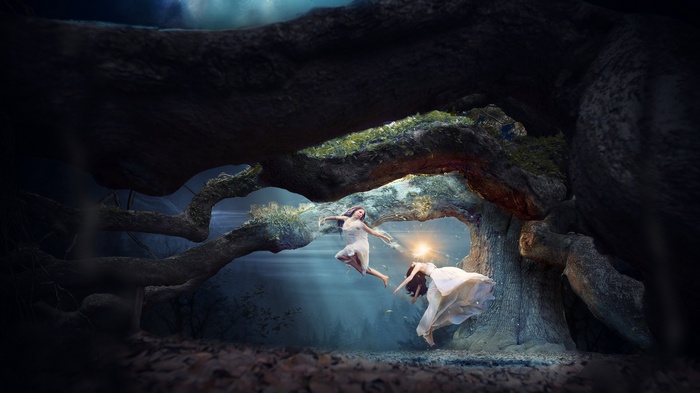 Two women in white dresses under a large tree