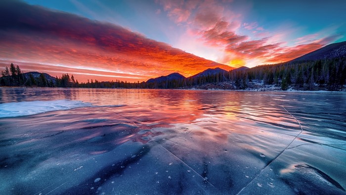 Sunrise over a frozen lake with mountains
