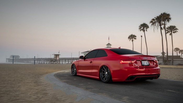 Red Audi RS5 on a beach near a pier