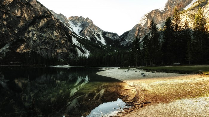 Body of Water Near Trees and Mountains at Sunset