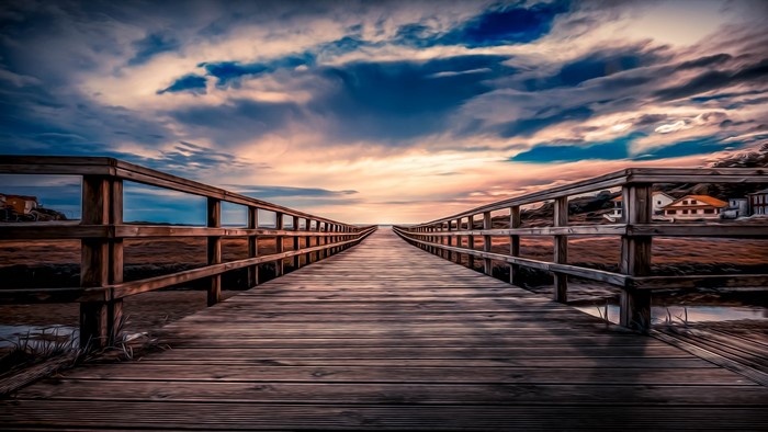 Wooden boardwalk leading to the ocean under a cloudy sky