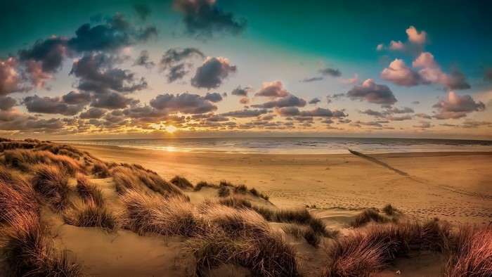 Sunset over a beach with sand dunes and ocean
