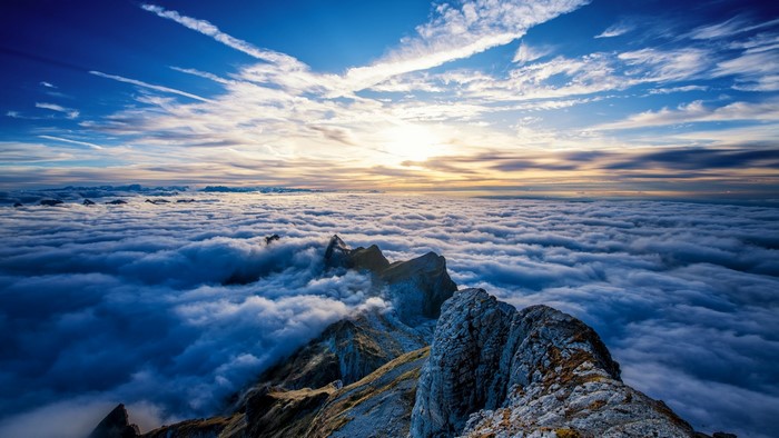 Mountain peaks above clouds at sunset