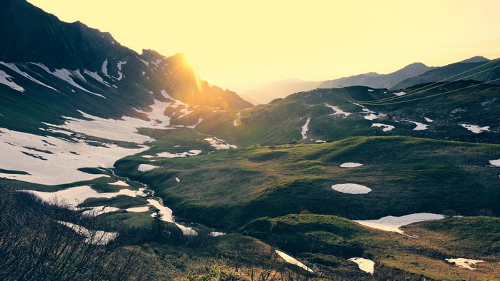 Mountain valley with snow patches at sunset