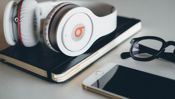 Beats headphones on a notebook with glasses and phone