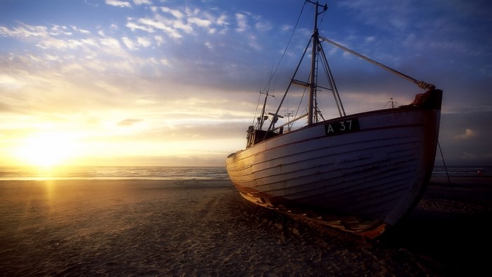 Fishing boat on a beach at sunset