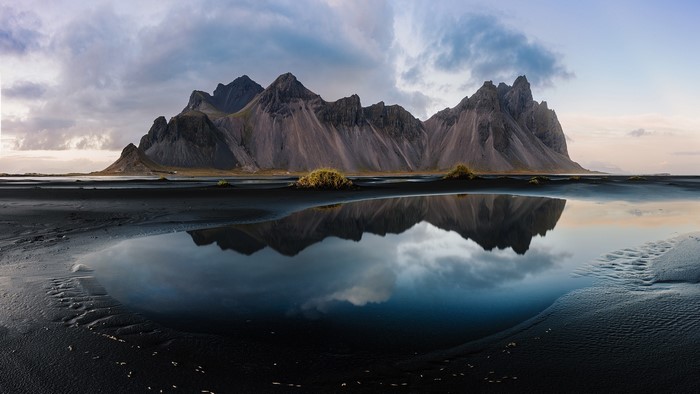 Mountains reflected in a tidal pool on black sand beach