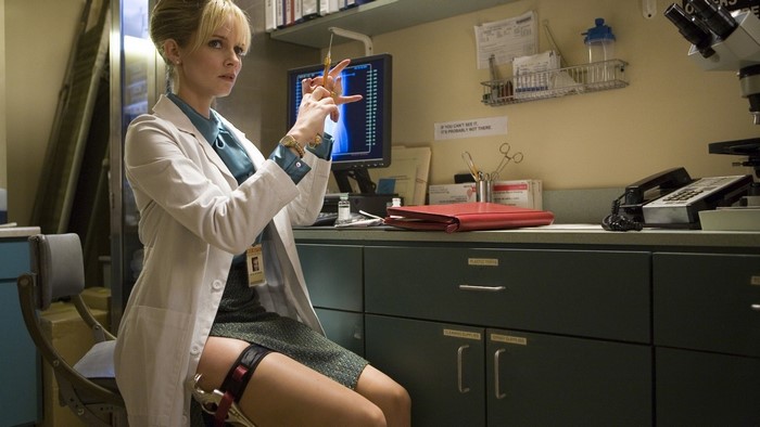 Woman in lab coat holding syringe