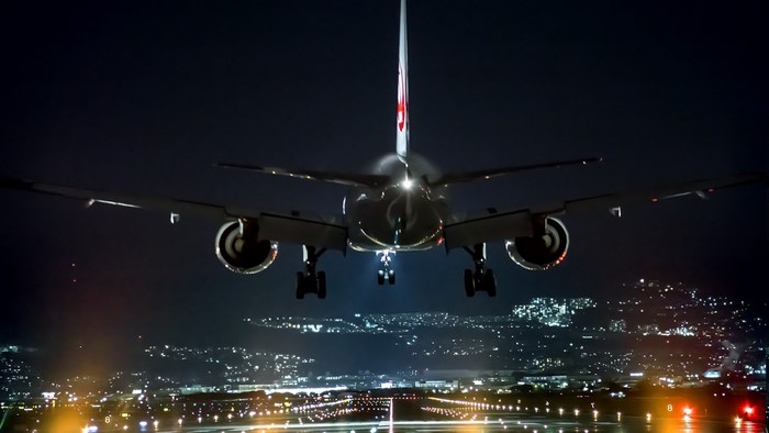 Airplane landing at night over city lights