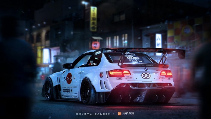 Modified white BMW M3 with large spoiler in a city at night