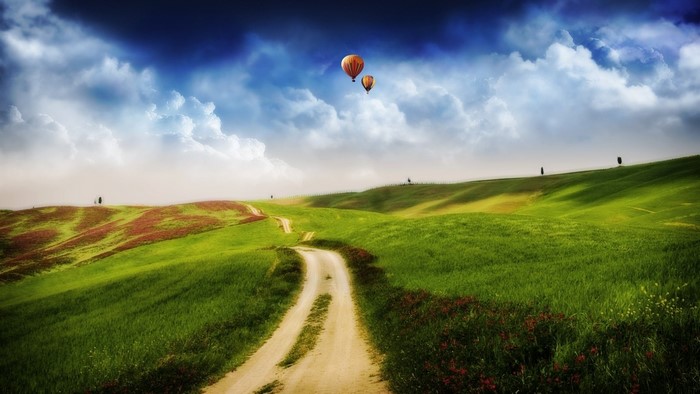 Hot air balloons over rolling green hills
