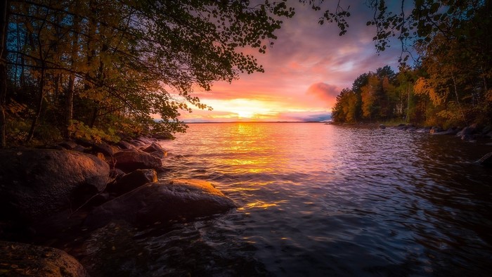 Sunset over a lake with trees and rocks