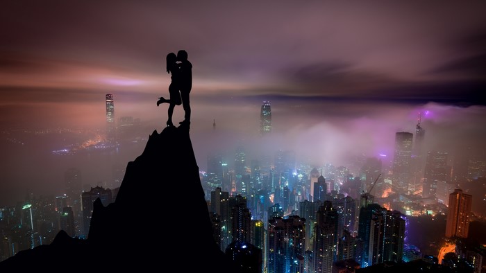 4K Silhouettes of a Couple Kissing on a Mountain Peak Overlooking a City