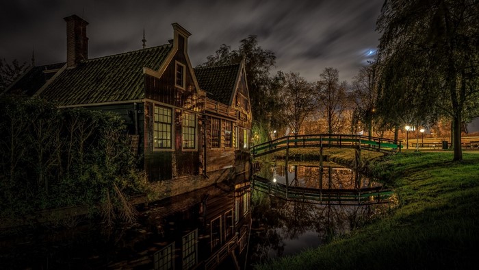 Old wooden house by canal at night