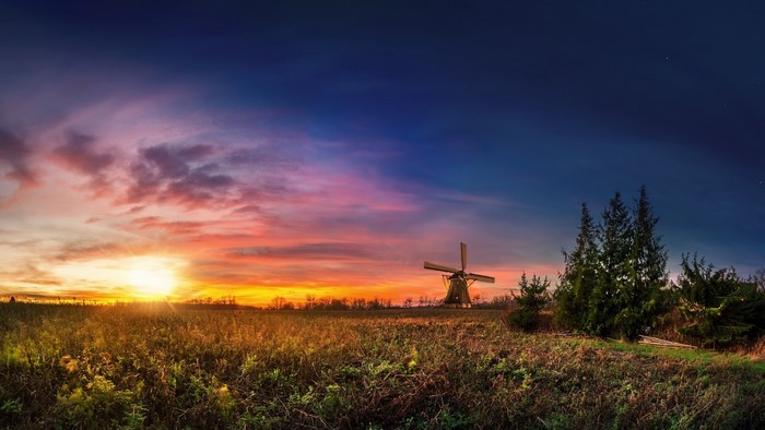 Sunset over a field with a windmill