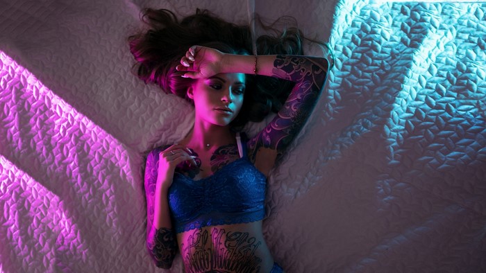 Vladlena Sidorenkova lying on a bed with tattoos