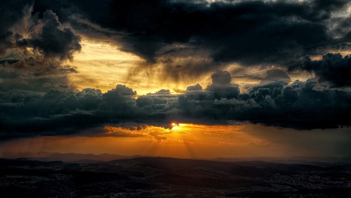 Dramatic sunset with dark clouds over a landscape