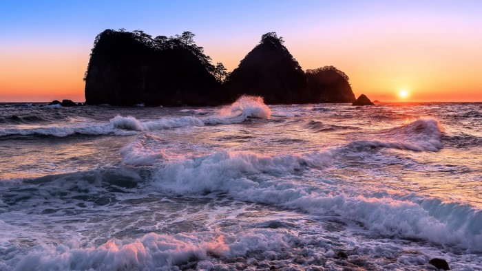 Ocean sunset with rocky islands and waves