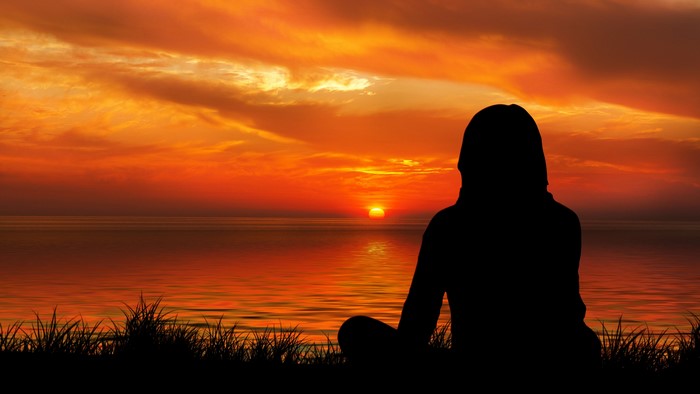 Silhouette of a person meditating at sunset