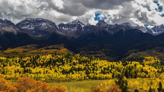 Autumn mountains with yellow trees and snow-capped peaks