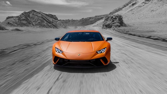 Orange Lamborghini Huracan driving on a road