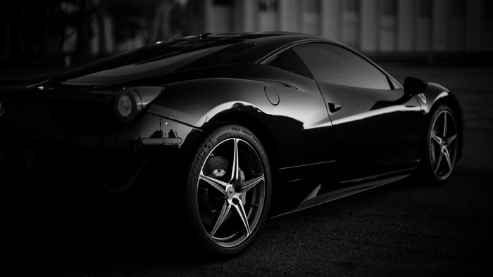 Black Ferrari sports car parked on asphalt