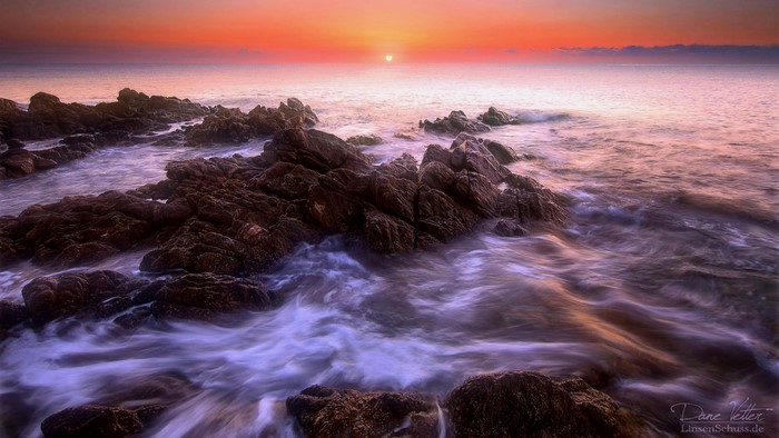 Sunset over rocky shore with ocean waves