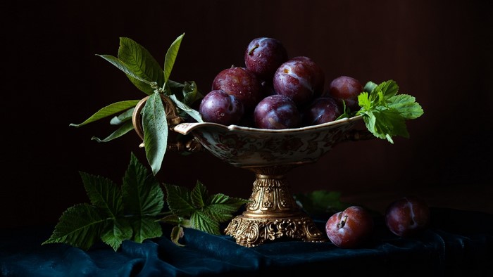 Plums in a decorative bowl with leaves