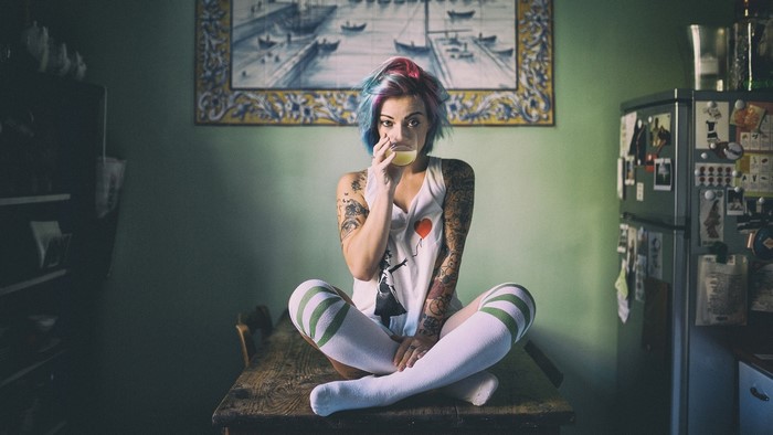 Woman with colorful hair drinking from a glass