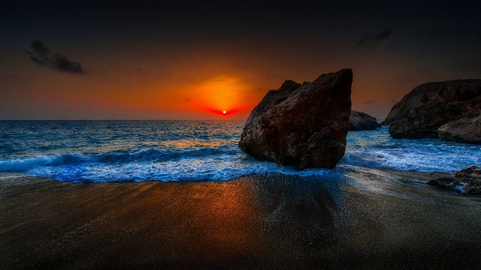Sunset over the ocean with rocks on the beach