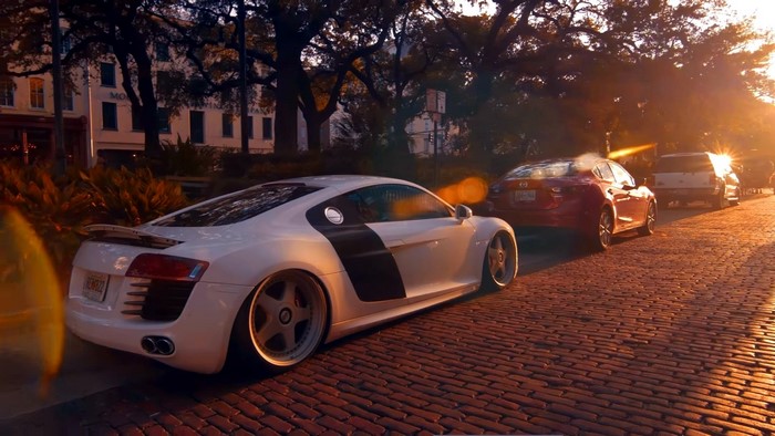 White Audi R8 parked on cobblestone street at sunset
