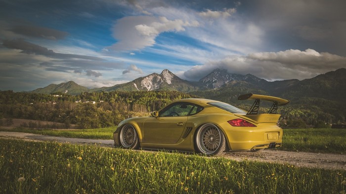Yellow Porsche Cayman with a large spoiler in the mountains