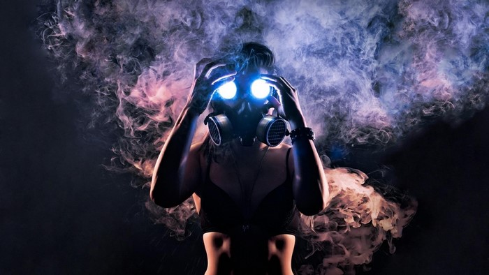 Woman in gas mask with glowing eyes and smoke