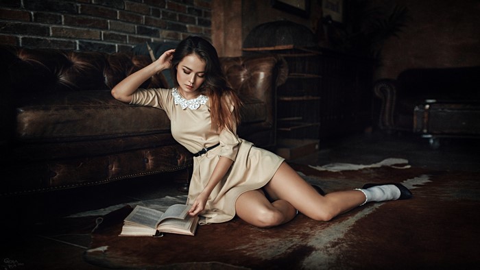 Girl in dress reading a book on the floor