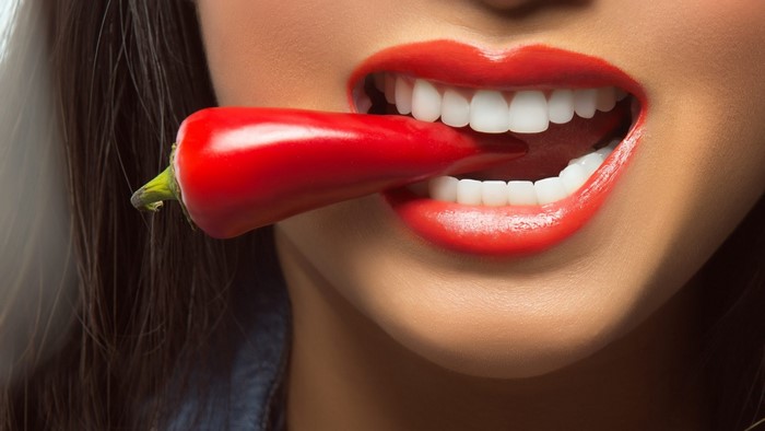 Woman biting a red chili pepper